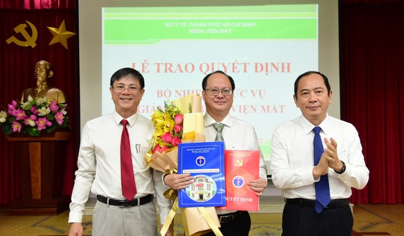Ông Tăng Chí Thượng - giám đốc Sở Y tế TP.HCM (phải) - cùng lãnh đạo Sở Nội vụ TP trao quyết định cho bác sĩ Lê Anh Tuấn